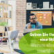 Eine Gruppe von 3 Menschen sitzt an einem Tisch in einem hellen Coworkingspace und unterhält sich, alle haben Laptops vor sich Tassen mit Getränken. Im Hintergrund ist eine Pinnwand mit Post-Its zusehen und ein Regal mit Ordnern.